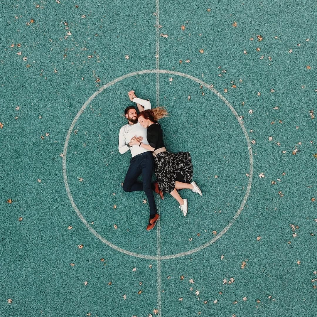 beautiful drone pose of couple on a green basketball field, Berlin